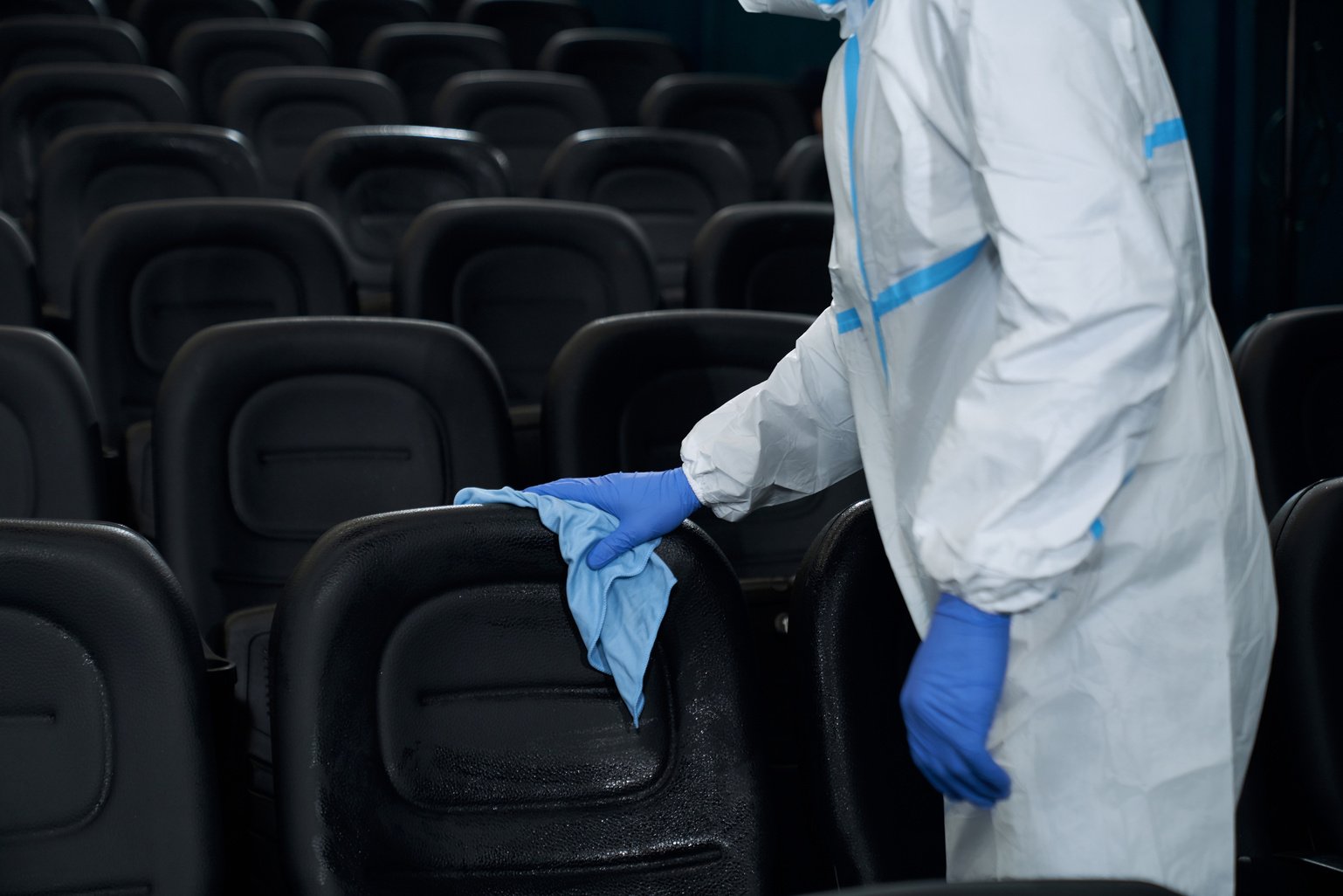 Worker holding rag and wiping chairs in cinema.