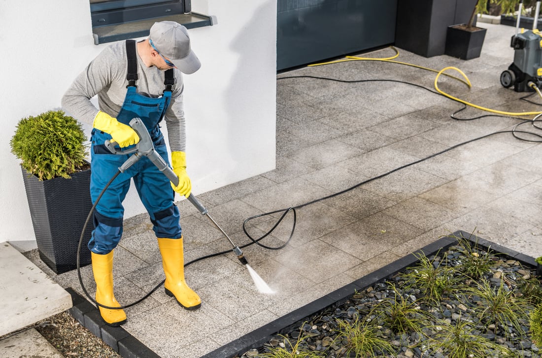 Men Pressure Washing His House Surrounding